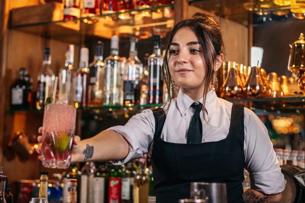 young bartender woman handing over a drink